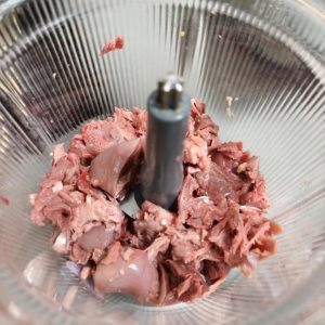 Smashing pigeon bones with a meat mallet on a cutting board