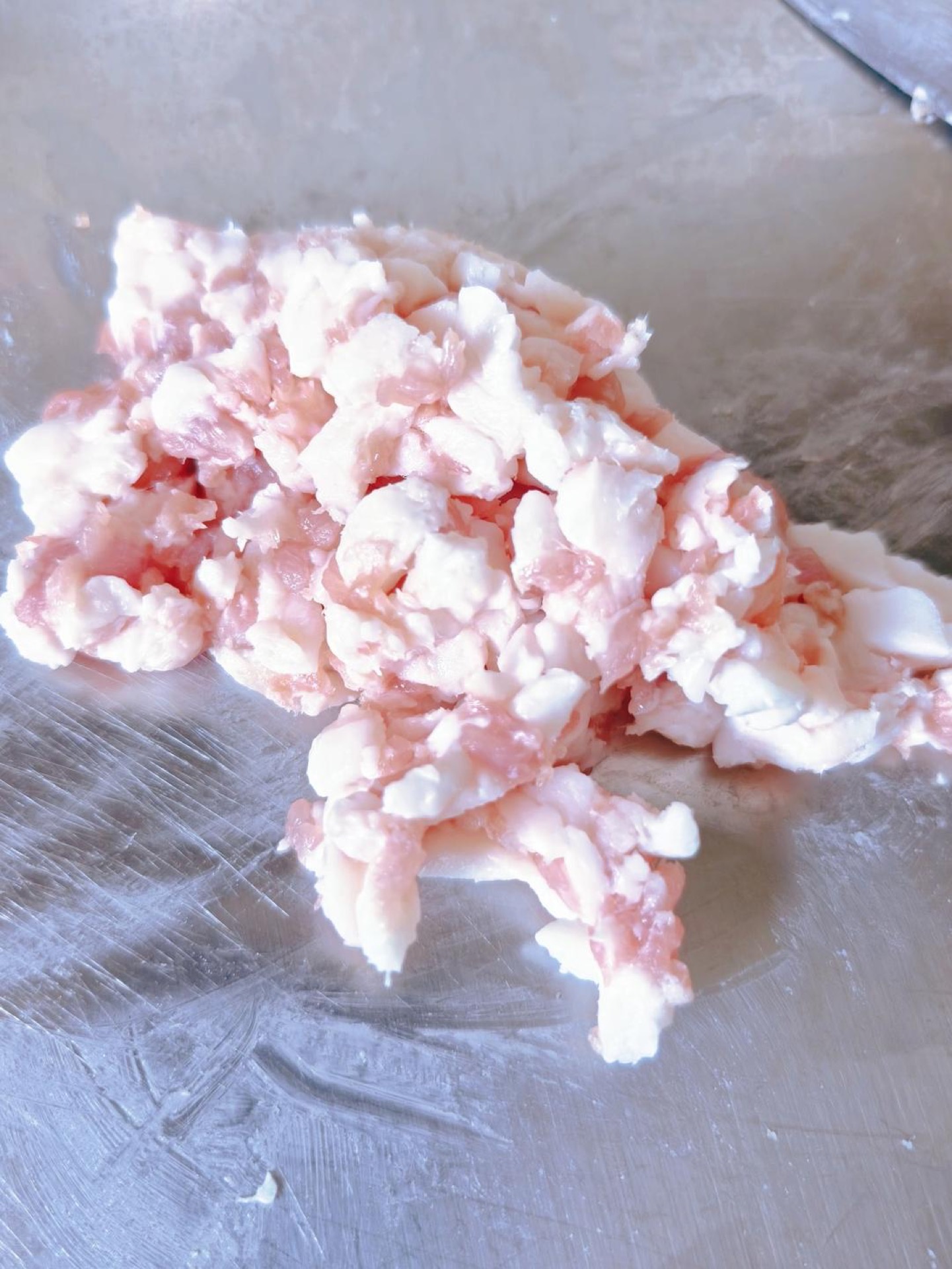 Minced pork belly being folded into minced pigeon