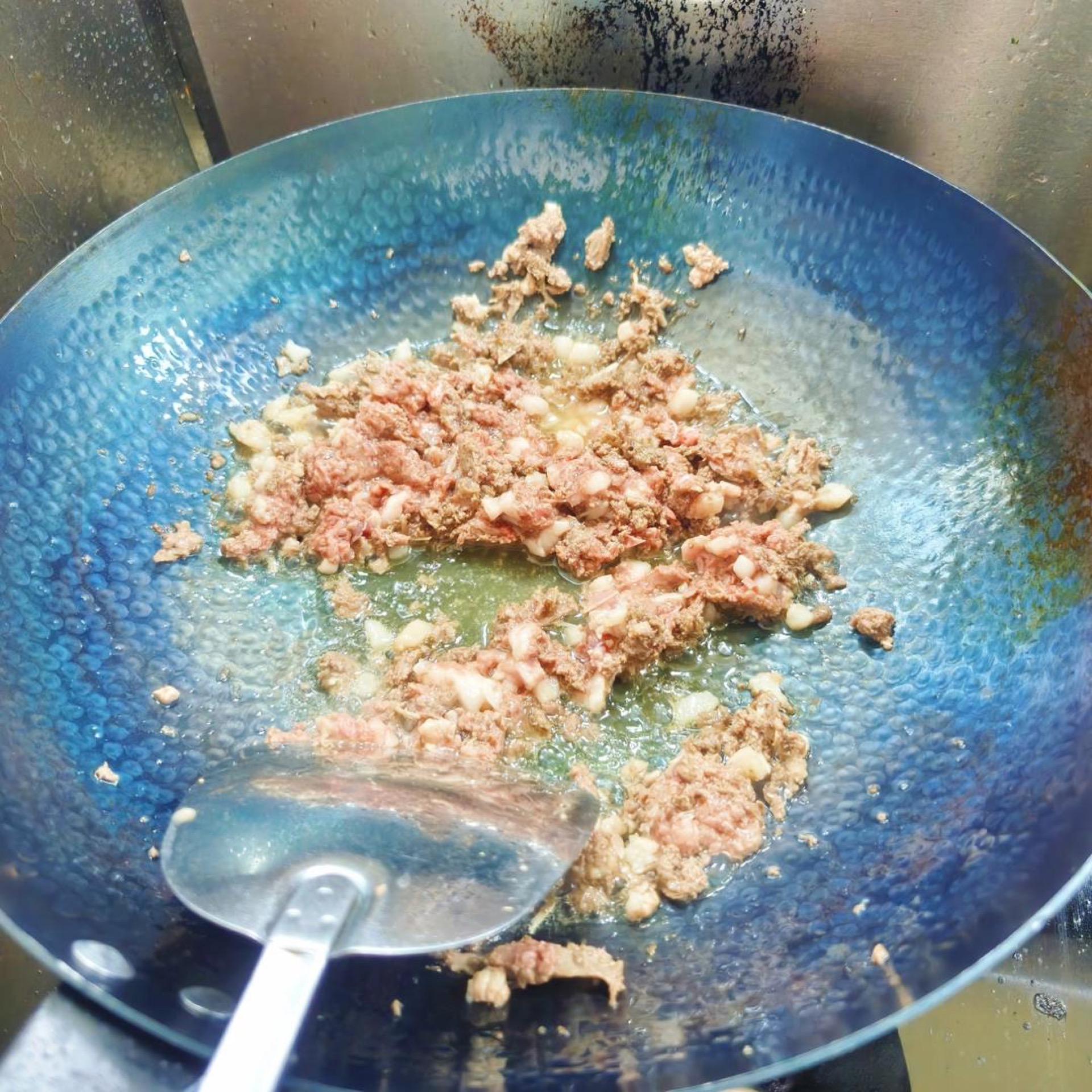 Minced pigeon hitting a hot wok with shimmering oil