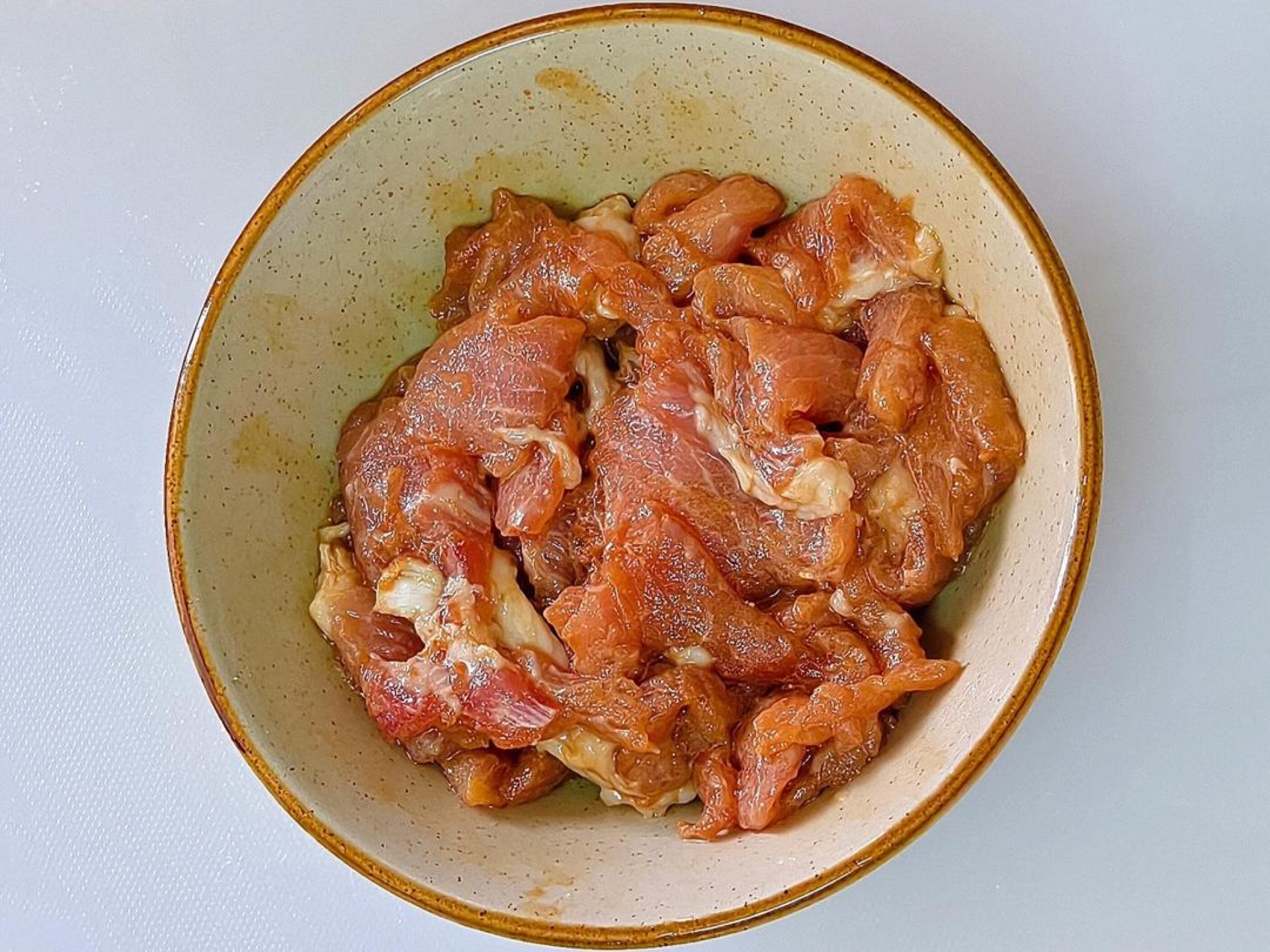 Place the sliced pork in a bowl with a little oil, salt, sugar, light soy sauce, dark soy sauce, and cornstarch, then mix well and let it marinate.