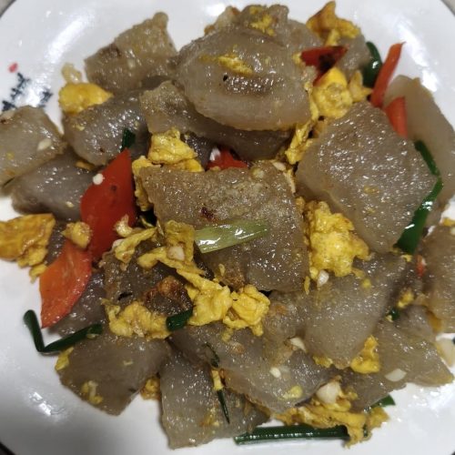 Stir-fried sweet potato starch with eggs served on a plate with peppers and scallions