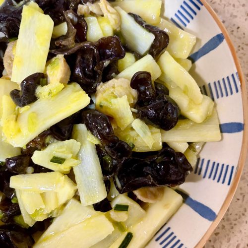 Stir-fried yam with black fungus served in a white bowl with scallions