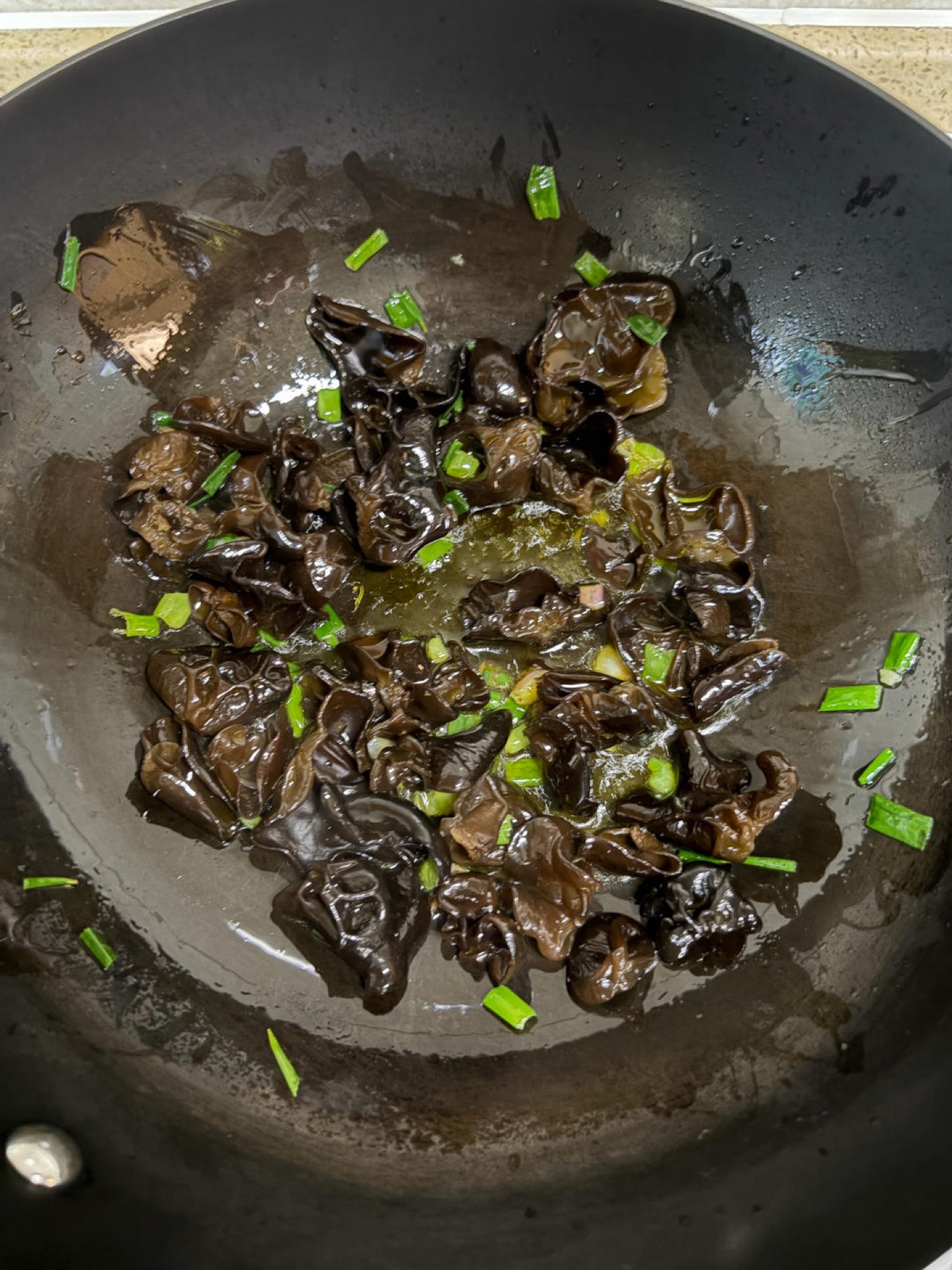 Heat vegetable oil in the wok and fry the minced scallion until fragrant, then add the black fungus and stir-fry for a dozen or so tosses.