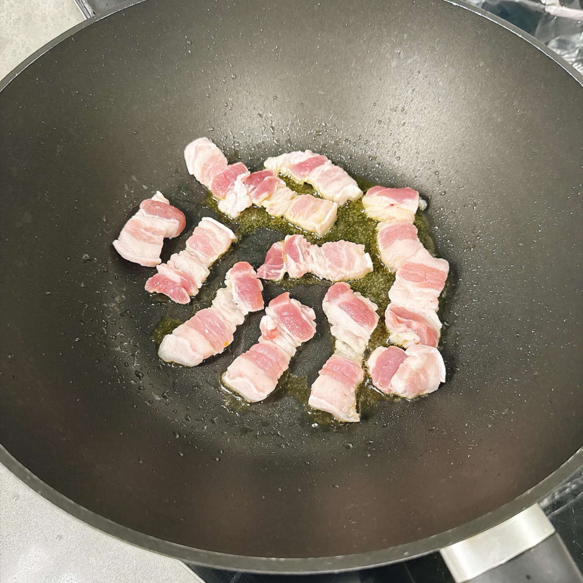 Heat oil in the wok and add the pork belly to sear.