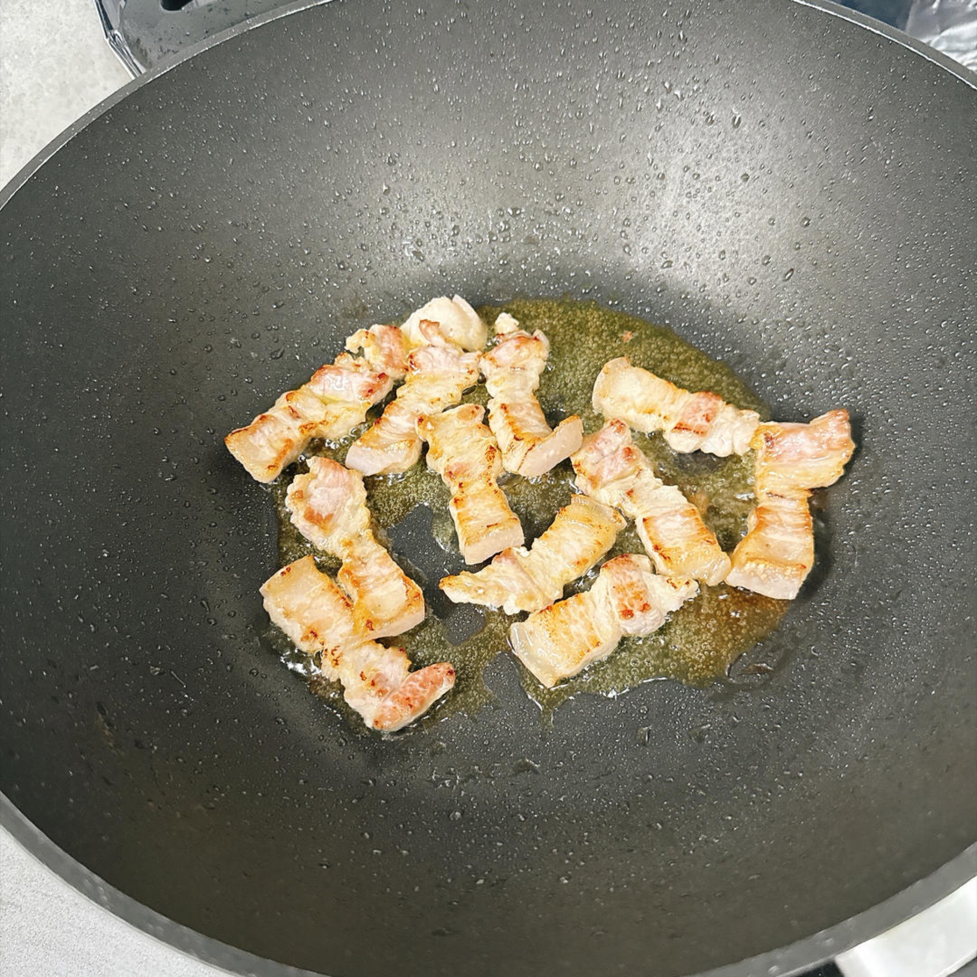 Fry the pork belly until it renders its fat and the edges turn golden.