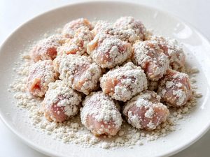 Press each marinated piece into the coarse sweet potato starch, shake off the excess, and lay the pieces flat to rest for 5 minutes so the coating hydrates and clings.