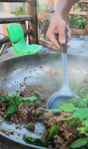 Folding Thai basil leaves into the pork