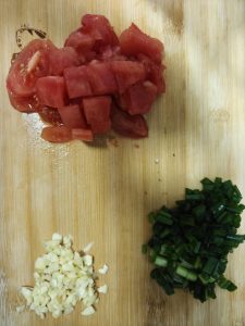 Dice the tomatoes into 1/2-inch cubes, mince the garlic, and finely chop the white parts of the scallions while slicing the green parts on the bias.