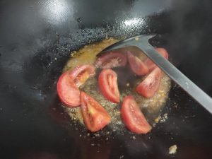 Stir-fry the tomato over high heat until it releases its juices, add about 20 g of water, then stir in the tomato paste.