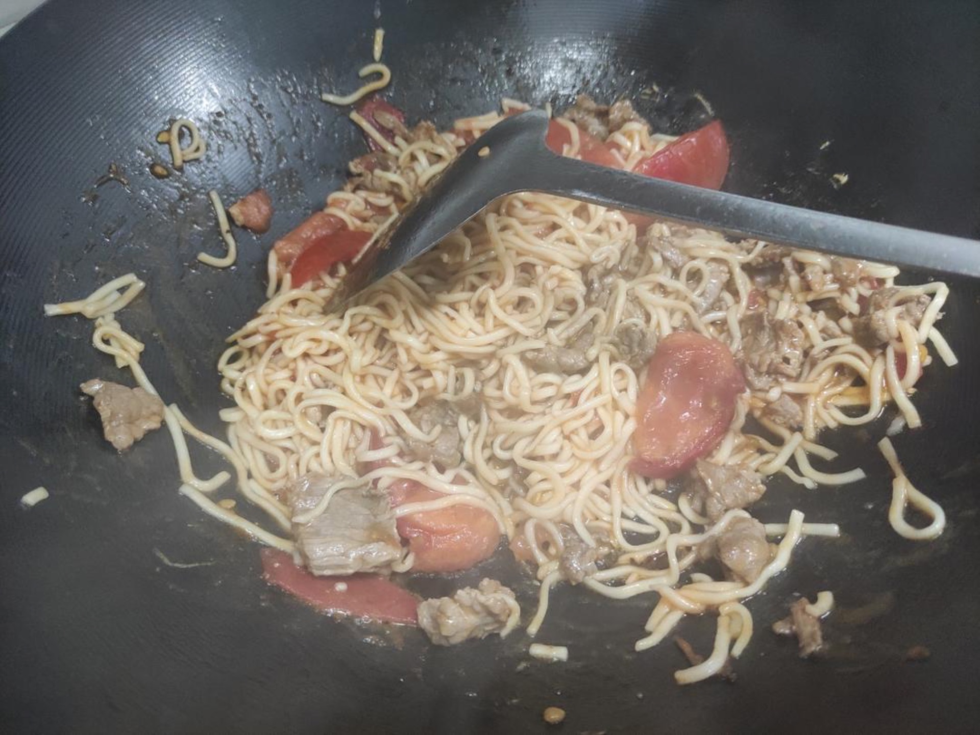 Add about 30 g of water to the wok, add the noodles, and simmer until only a little sauce remains, then add the pork slices and cook until the liquid is gone and the pork is cooked