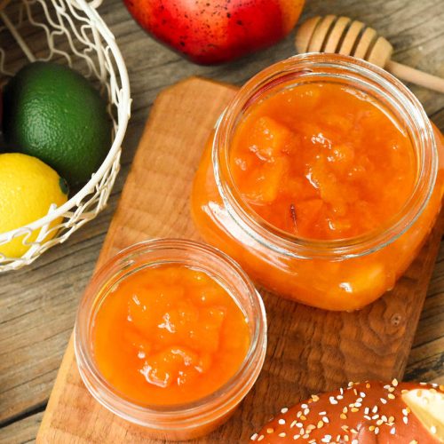 Jar of homemade vanilla peach and pear jam with fresh fruit