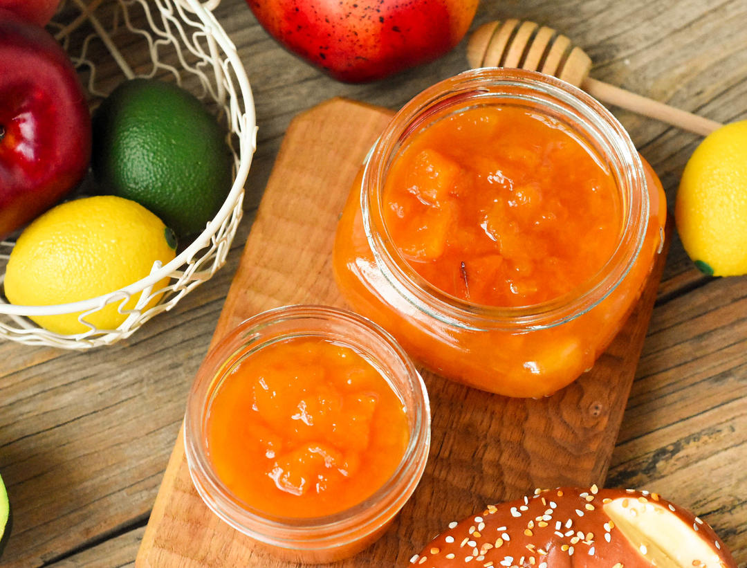 Jar of homemade vanilla peach and pear jam with fresh fruit