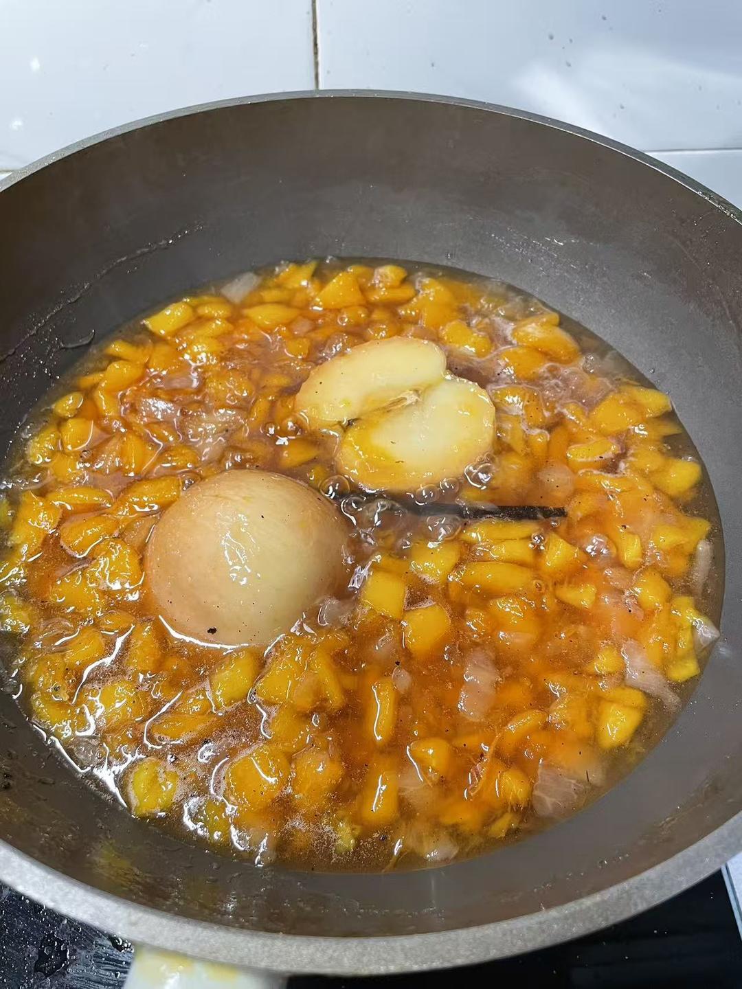 Covered pot of peach and pear jam simmering on low heat