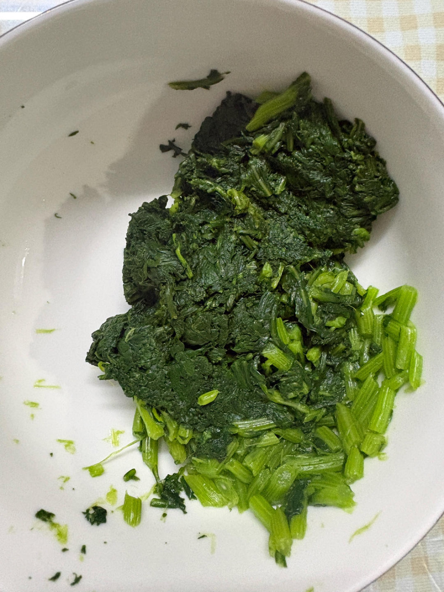 Squeeze the cooled greens firmly in your hands to press out the water, chop or snip them into small pieces, then squeeze them dry a second time.