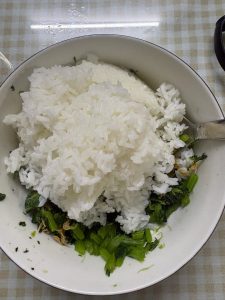 Add the hot cooked rice to the bowl and fold it through the dressed greens until every grain is coated and glossy.