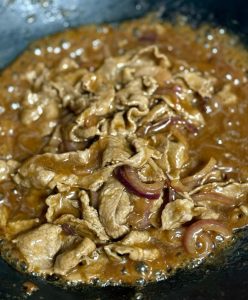 Pour in the sauce you mixed ahead — 2 tablespoons light soy sauce, ½ tablespoon dark soy sauce, 1 tablespoon Shaoxing wine, a pinch of sugar, 1 heaping tablespoon cornstarch, and a