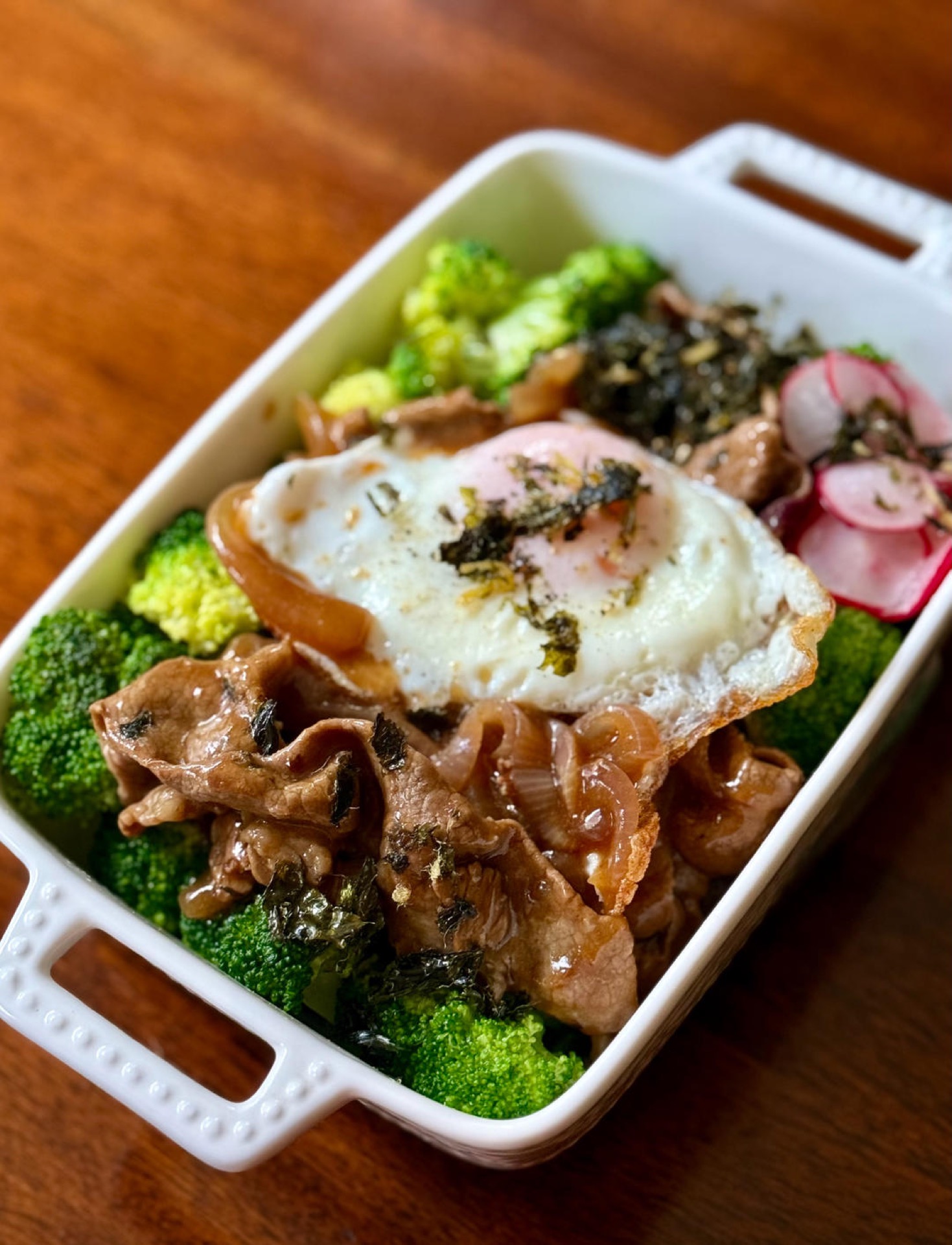 Mound the multigrain rice in a large bowl, arrange the broccoli, pickled radish, glazed beef, and fried egg on top, and finish with seasoned seaweed flakes, black pepper sea salt,