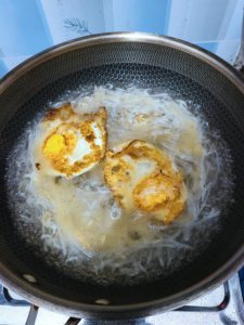 Return the fried egg pieces to the wok, pour in the boiling water, and bring everything to a rolling simmer for 5 minutes.