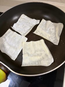 Wonton wrappers frying in a lightly oiled pan until golden