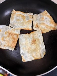Golden pan-fried wonton wrappers resting on a plate