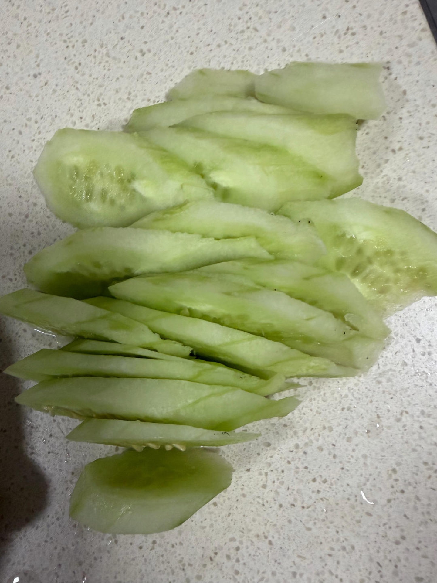 Thin slices of peeled cucumber on a cutting board