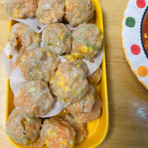 Steamed wonton wrapper dumplings filled with vegetables and egg on a bamboo steamer