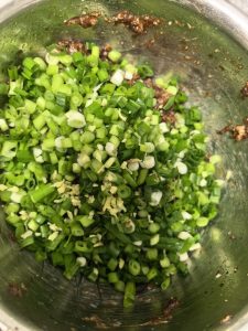 Take the chilled meat out after two hours, then add minced ginger, sliced scallions, and sesame oil, and mix well.