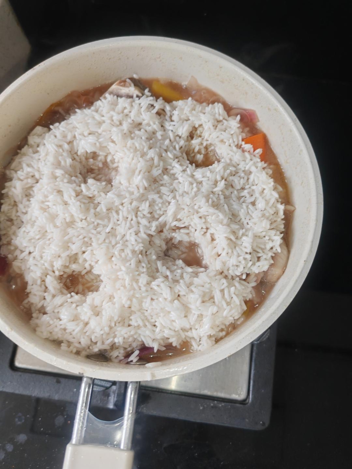 Spread the rinsed rice over the top, leaving the edges slightly open for steam to escape, poke a few holes in the middle, and after 15 minutes pour the reserved half bowl of broth