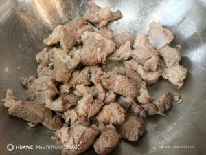 Sear the lamb in the wok until the meat tightens and browns.