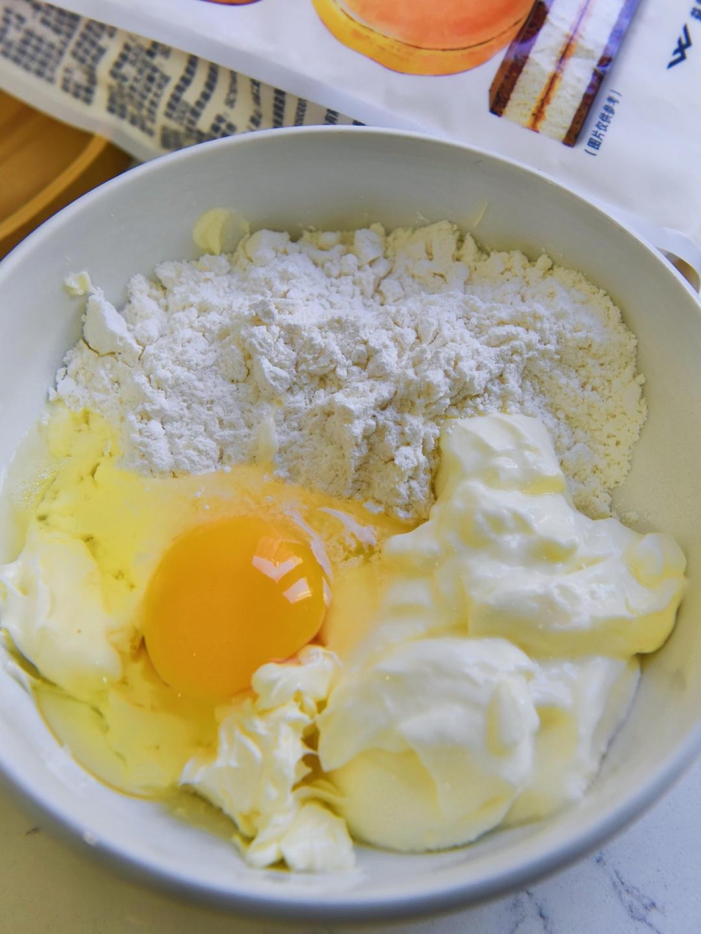 Whisking egg, yogurt, butter, and sugar in a bowl