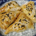 Air fryer apple pie hand pies on a plate with a crisp golden shell and sesame seeds