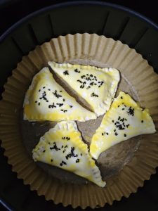 Grease the parchment paper with oil, set the pie parcels on it, brush them with the egg yolk wash, and scatter on a few black sesame seeds.