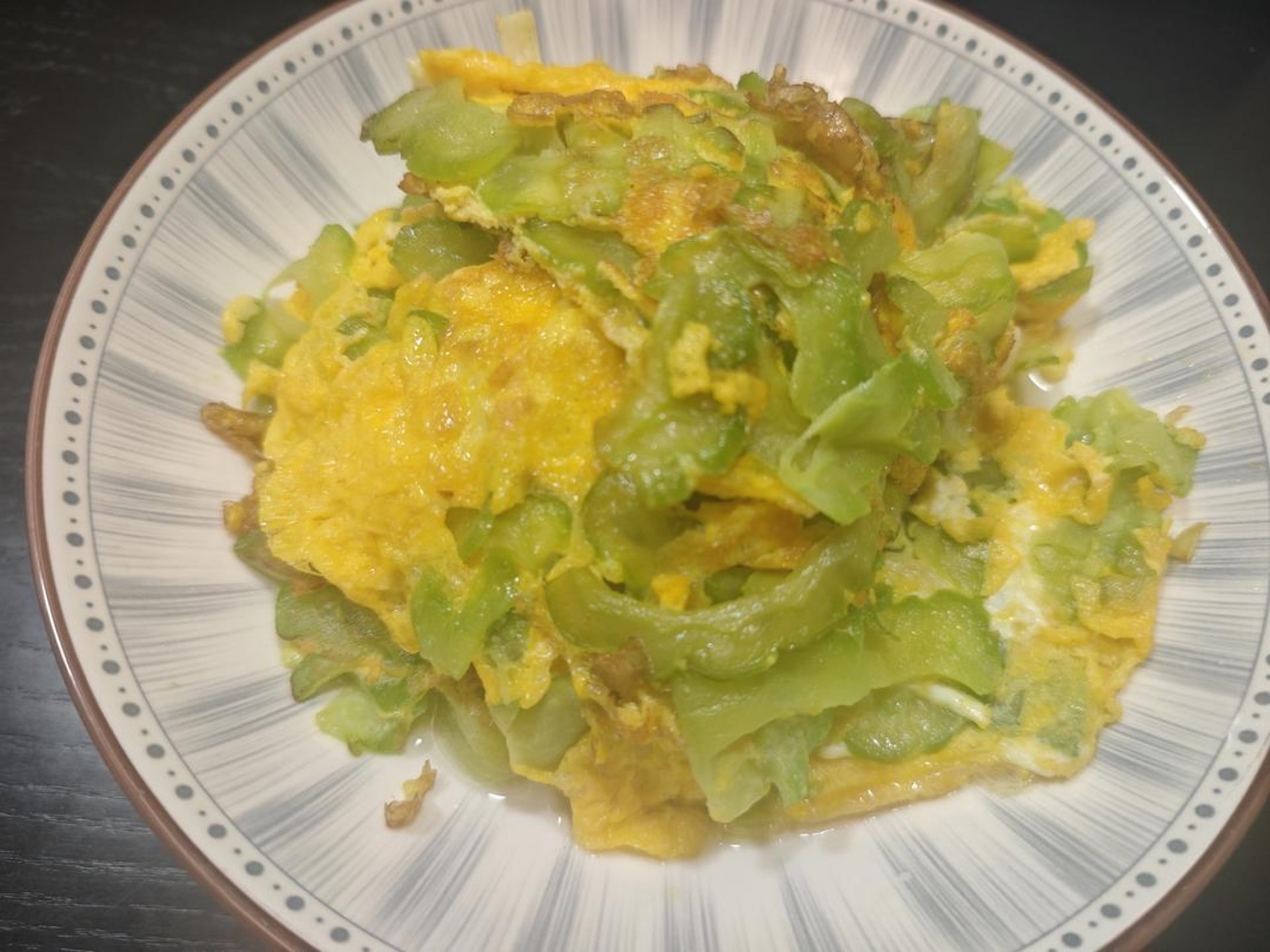 Bitter melon omelette in a wok, golden egg set over translucent slices of bitter gourd