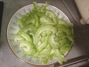 Halve the bitter melon lengthwise, scrape out the seeds and white pith with a spoon, and slice it crosswise into 1/8-inch thin half-moons; smash the garlic cloves with the flat sid