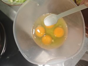 Crack the four eggs into a bowl, add half a teaspoon of salt, and whisk until the yolks and whites are completely combined and slightly frothy.