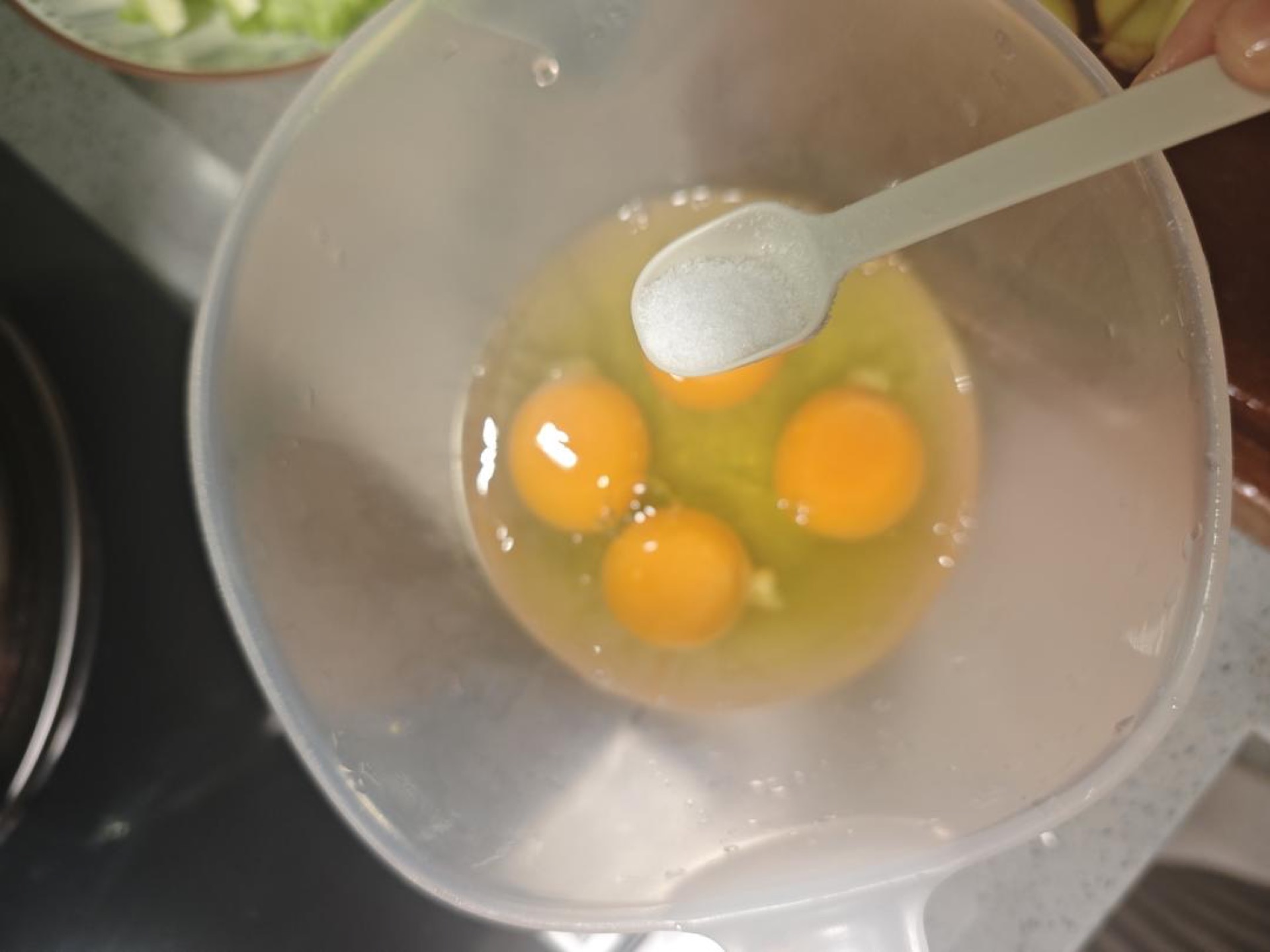 Crack the four eggs into a bowl, add half a teaspoon of salt, and whisk until the yolks and whites are completely combined and slightly frothy.