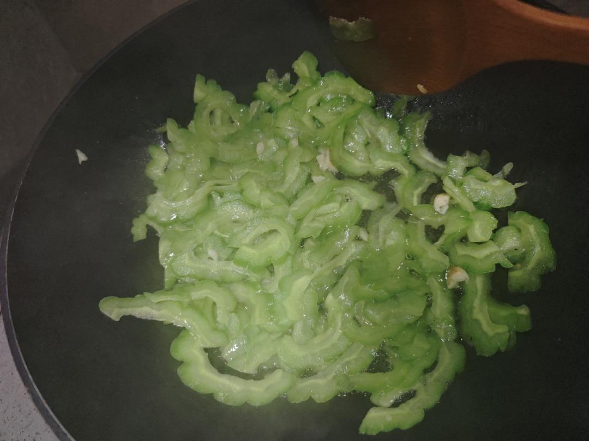 Add the sliced bitter melon to the wok and stir-fry for 4 to 6 minutes, until the slices soften, lose their raw edge, and turn translucent.