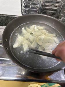 Add about 1 teaspoon (1–2 g) of salt to the warm water, then slide the frozen dumplings in directly from the freezer without thawing. Use at least 4–5 times the dumplings' volume i