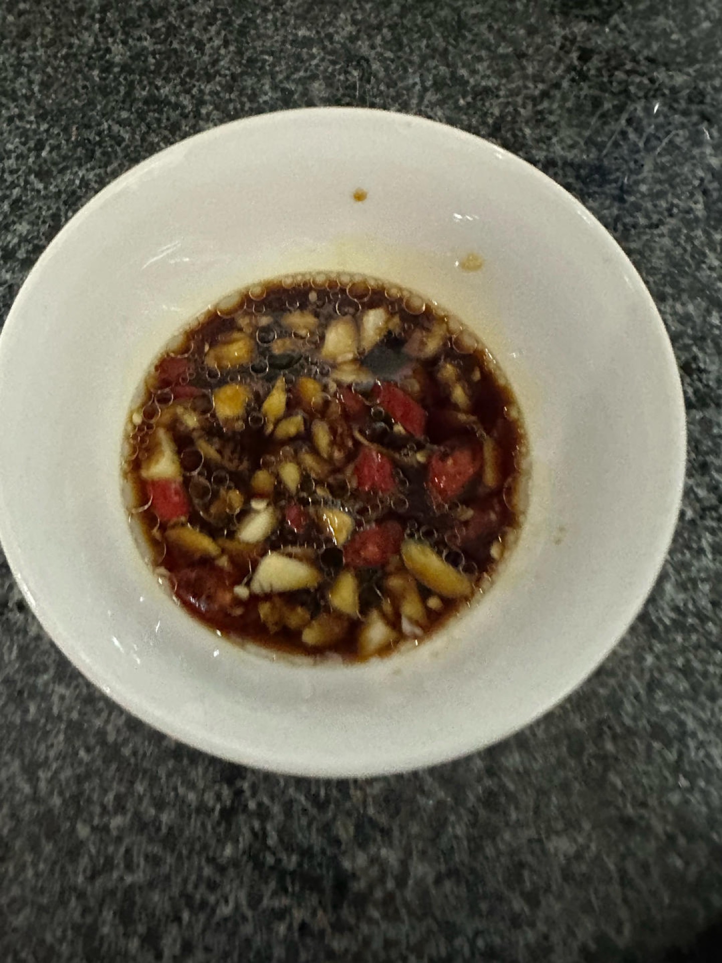 The dip is the soul of the plate: minced garlic, sliced bird's eye chili, light soy sauce, aged black vinegar, and a few drops of toasted sesame oil, with the soy sauce and vinegar