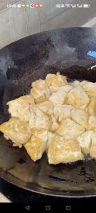 Heat a pan with oil, sprinkle in a little salt, and add the tofu, frying until both sides are golden brown as shown.