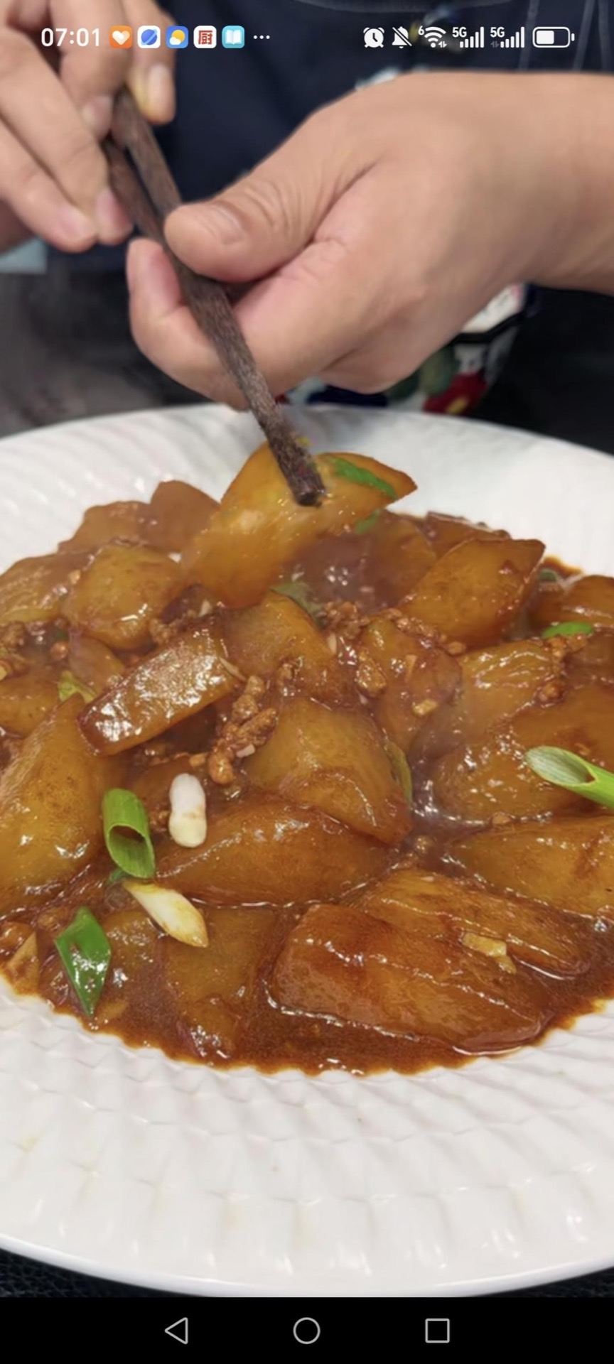 Braised daikon with minced pork served in a white bowl, glossy radish chunks topped with green scallions