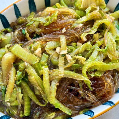 Braised napa cabbage with vermicelli in a dark wok, glossy noodles tangled with soft cabbage and scallions