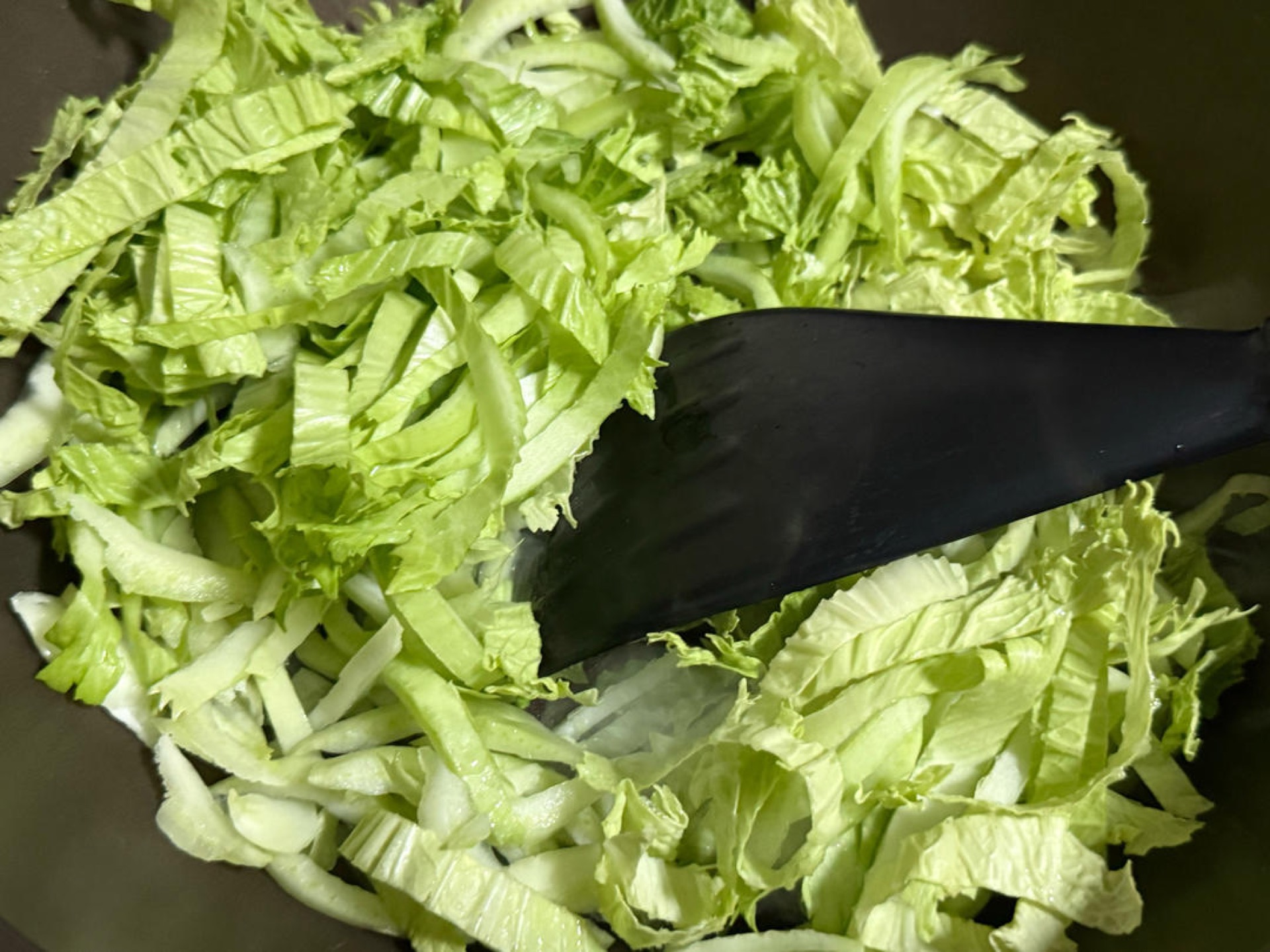 Heat the wok over medium heat, add the oil and the two star anise, then add the cabbage, pour in a small bowl of pork bone broth, sprinkle in some salt, cover with a lid, and let i