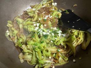 Add the soaked vermicelli to the wok and scatter the chopped scallions and minced garlic over the top.