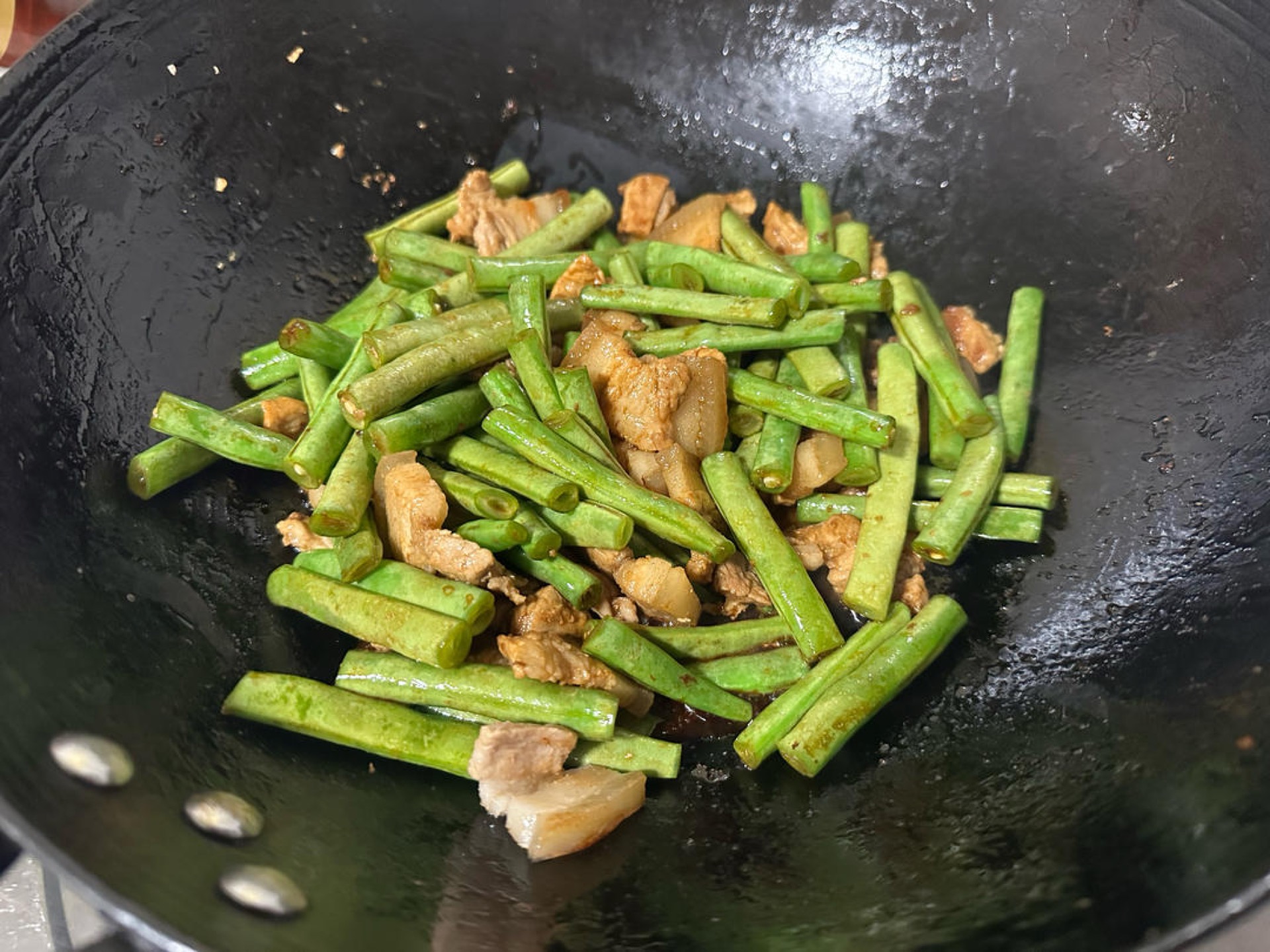Add the green beans and stir-fry for 2 to 3 minutes, then season with Shaoxing wine, light soy sauce, dark soy sauce and salt, using a little extra dark soy sauce for color.