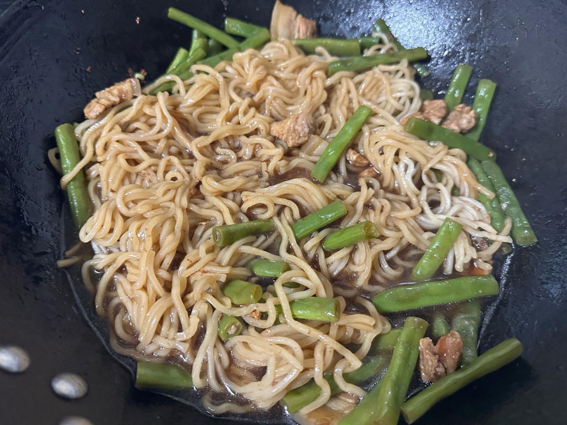Lift the lid, flip the noodles over, pour the reserved half bowl of broth back in so the top noodles soak it up, and steam for another 5 minutes, checking often so nothing burns; w