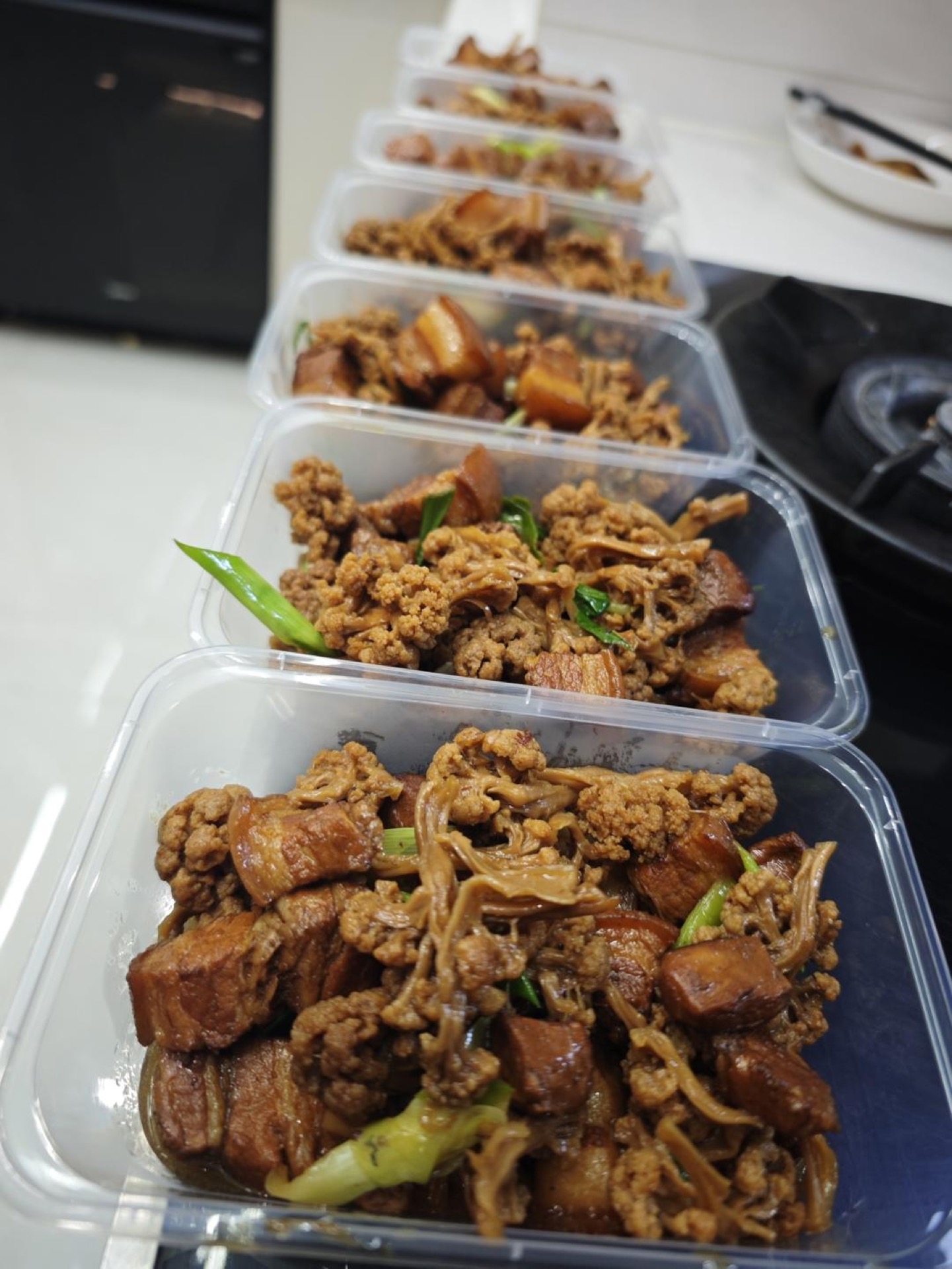 Braised pork belly with dried cauliflower in a dark sauce, finished with garlic sprouts