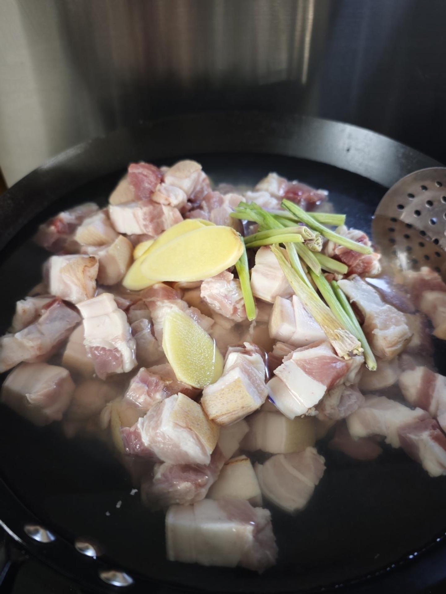 Add cold water, scallion, ginger and Shaoxing wine, bring to a rolling boil over high heat and cook for 2 to 3 minutes, then scoop the pork out, rinse away the scum under warm wate