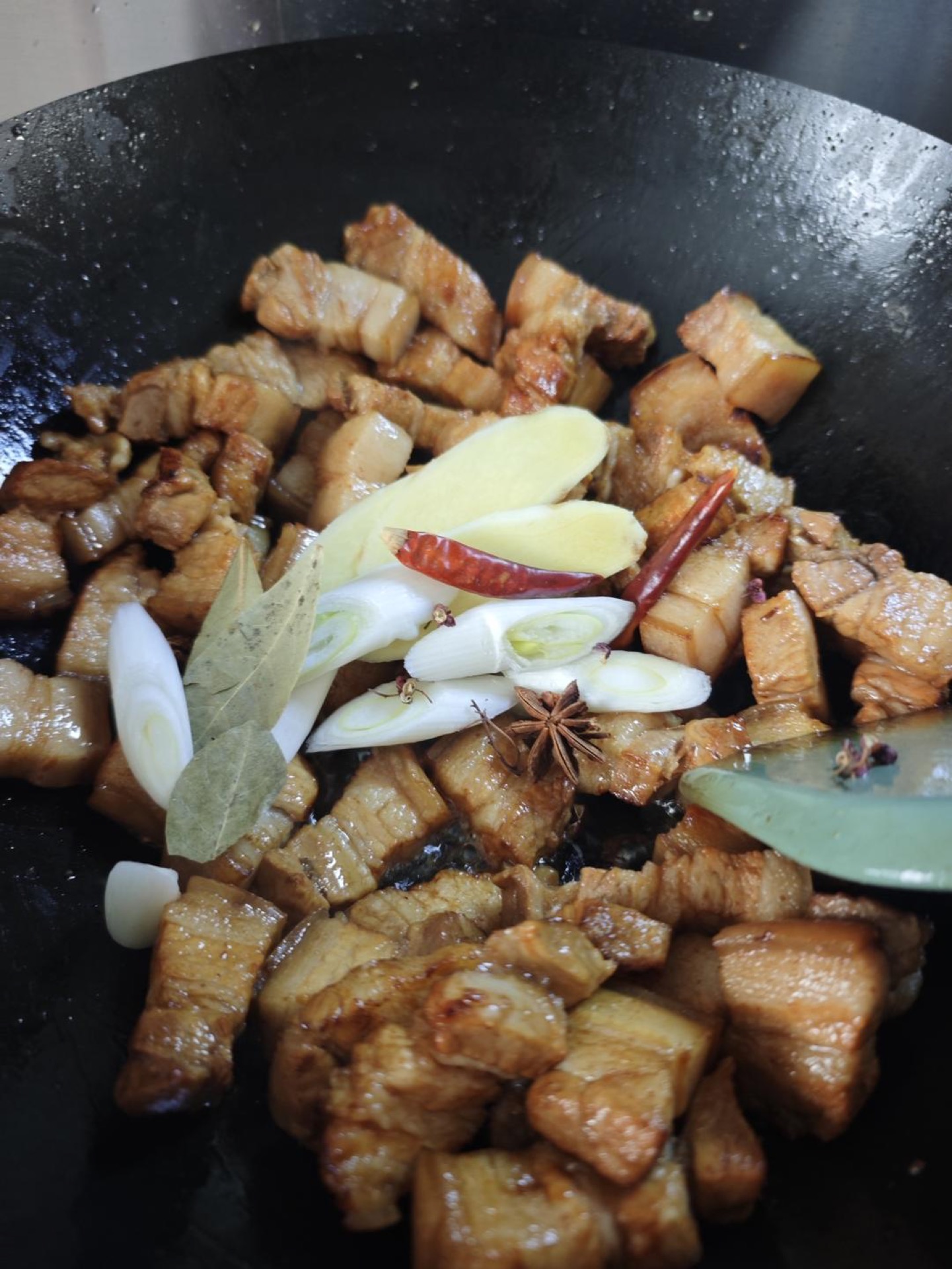 Add the scallion, ginger and the whole spices — star anise, bay leaf, cinnamon, chilies and Sichuan peppercorns — and stir-fry until their fragrance comes out.