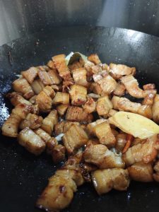 Once a good amount of fat has rendered out, drizzle a circle of Shaoxing wine, two circles of light soy sauce and one and a half circles of dark soy sauce around the edge of the wo